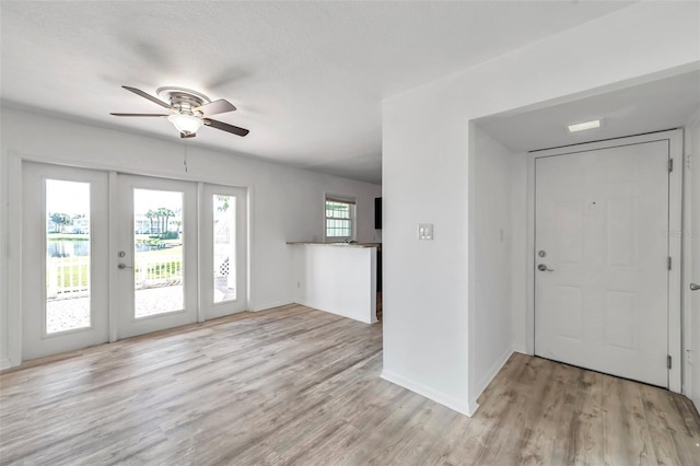 foyer featuring baseboards, french doors, a ceiling fan, and light wood-style floors