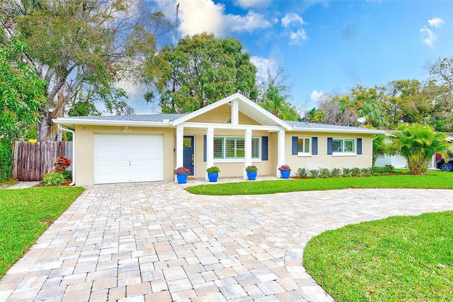 single story home with a garage, a front lawn, decorative driveway, and fence