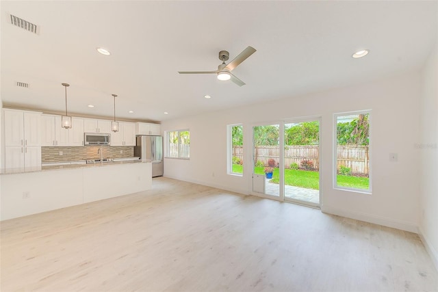 unfurnished living room with recessed lighting, a sink, light wood-style flooring, and baseboards