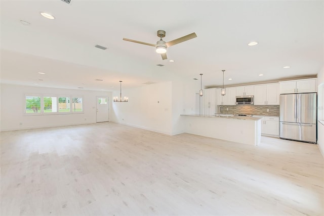 unfurnished living room with light wood-type flooring, visible vents, recessed lighting, and ceiling fan with notable chandelier