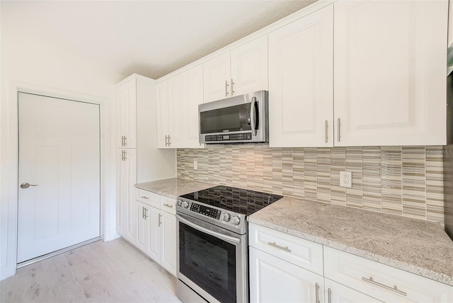 kitchen featuring light stone countertops, white cabinetry, stainless steel appliances, and decorative backsplash