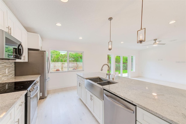 kitchen featuring decorative backsplash, stainless steel appliances, white cabinetry, pendant lighting, and a sink