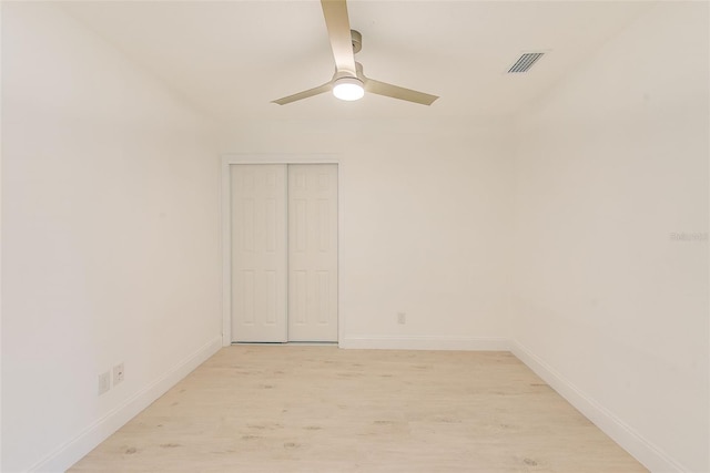 empty room featuring light wood-type flooring, ceiling fan, visible vents, and baseboards