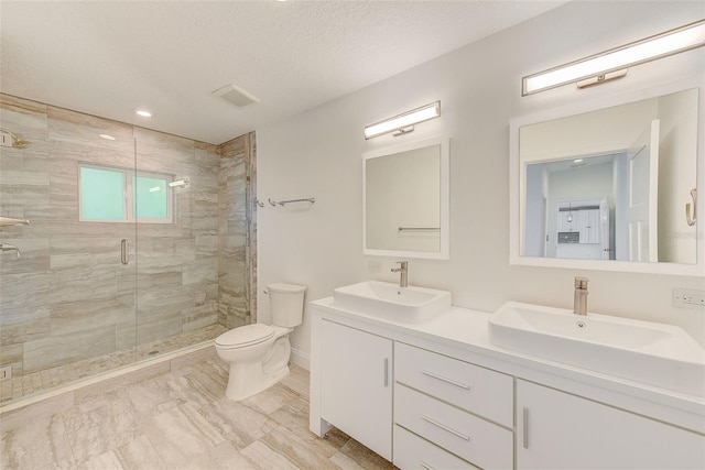 full bath with toilet, a shower stall, double vanity, and a sink