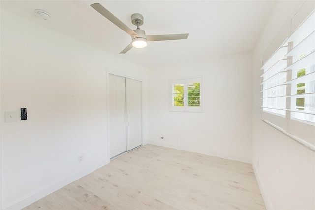 empty room featuring light wood-style floors, ceiling fan, and baseboards