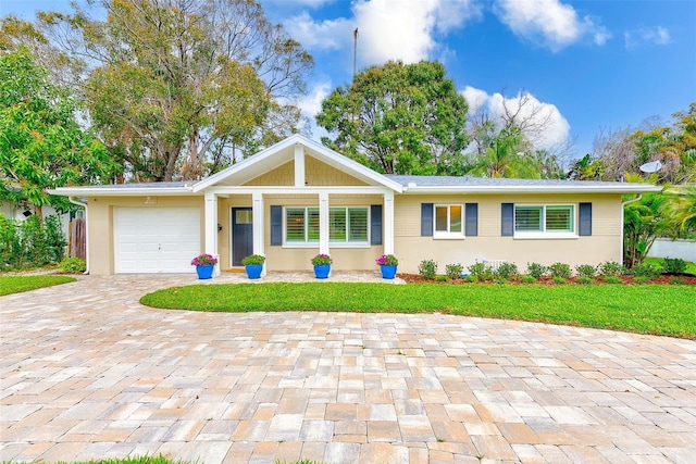 ranch-style house featuring a garage, a front lawn, and decorative driveway