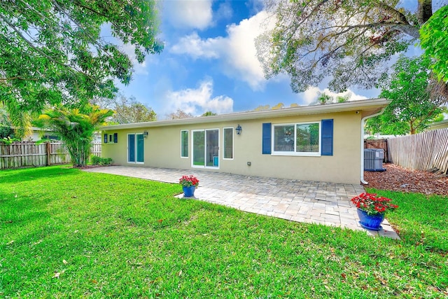 rear view of house featuring a yard, a fenced backyard, a patio, and stucco siding