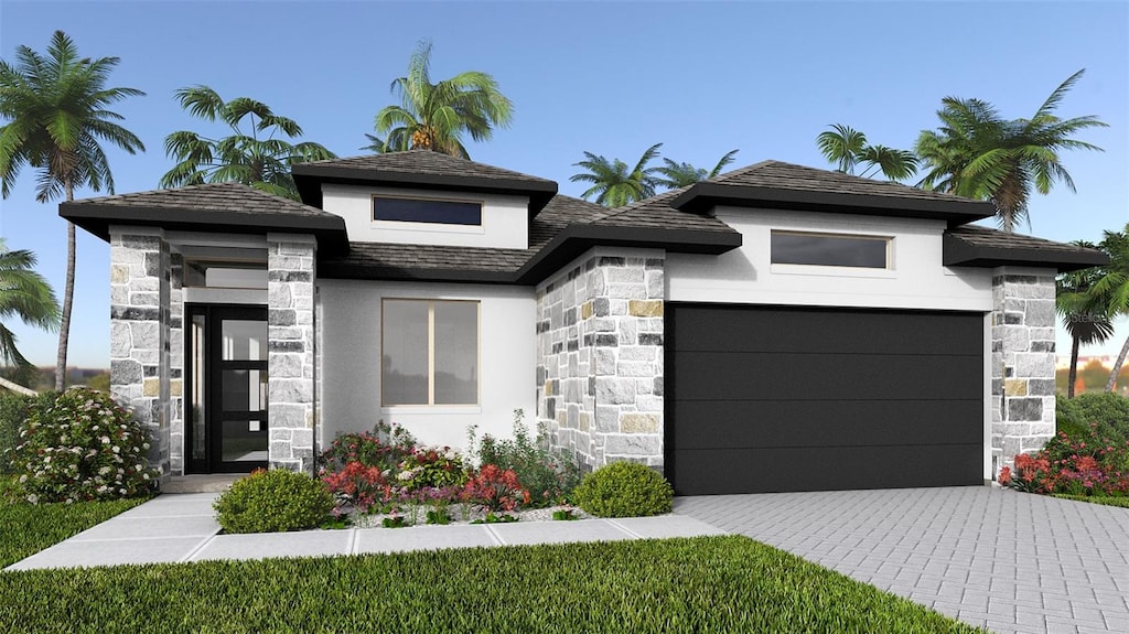 prairie-style house featuring a garage, stone siding, decorative driveway, and stucco siding