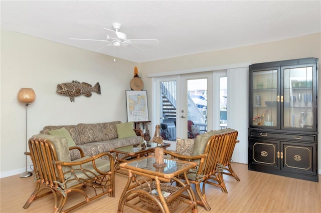 living room featuring light wood-style floors, baseboards, and a ceiling fan