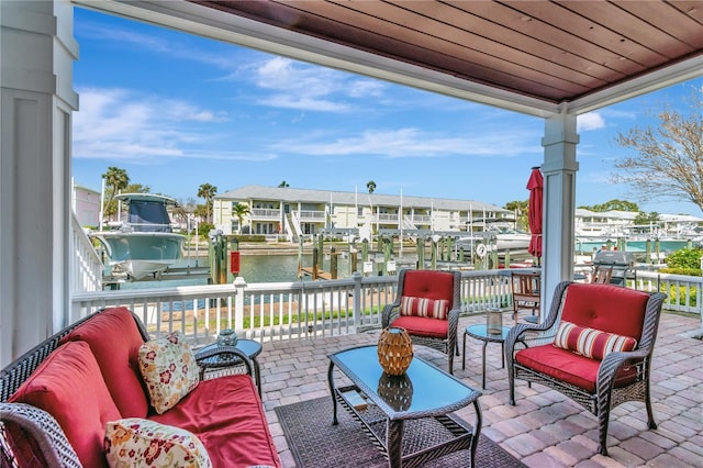 view of patio with outdoor lounge area, a boat dock, boat lift, and a water view