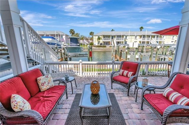 view of patio featuring boat lift, a water view, a boat dock, a residential view, and an outdoor living space