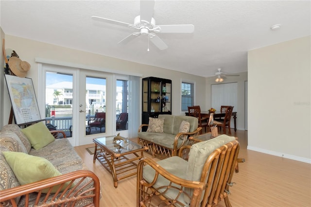 living room with french doors, light wood-style flooring, ceiling fan, a textured ceiling, and baseboards