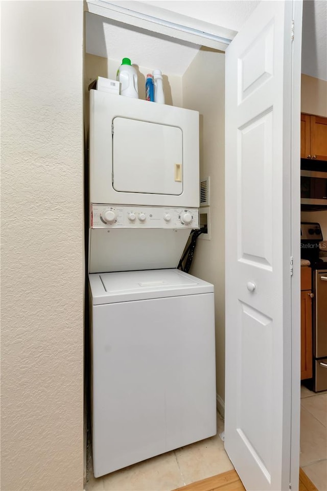 laundry room featuring stacked washing maching and dryer, laundry area, and a textured wall