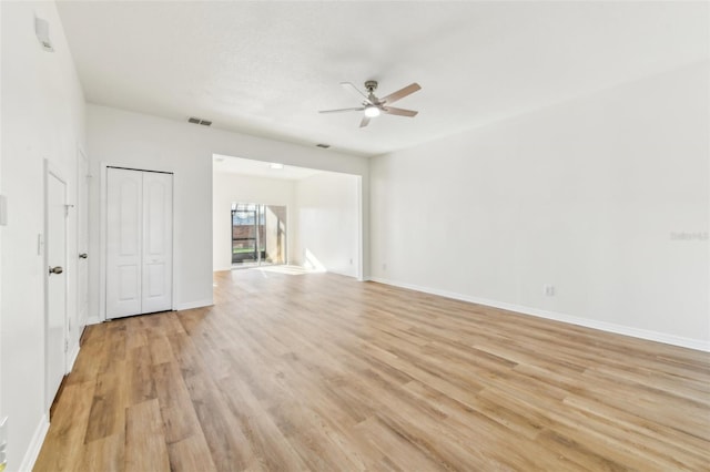 empty room featuring ceiling fan, light wood-type flooring, visible vents, and baseboards