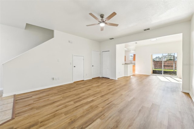 unfurnished living room with visible vents, ceiling fan, light wood-style flooring, and baseboards