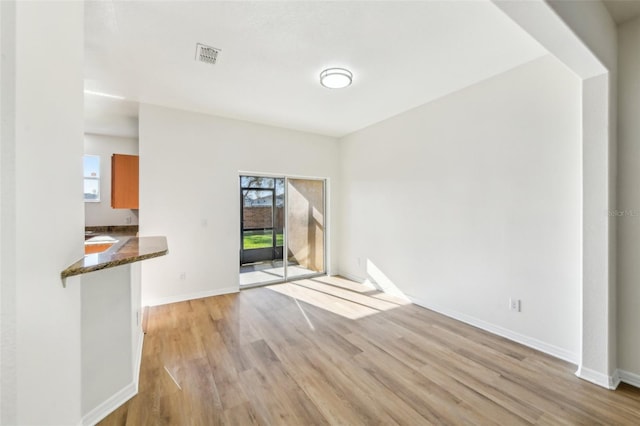 unfurnished living room with baseboards, visible vents, and light wood-style floors