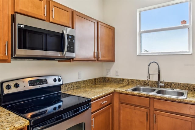 kitchen featuring brown cabinetry, stainless steel appliances, and a sink