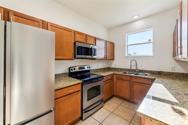 kitchen featuring brown cabinets, light tile patterned floors, stainless steel appliances, recessed lighting, and a sink