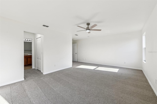 empty room with carpet flooring, ceiling fan, visible vents, and baseboards