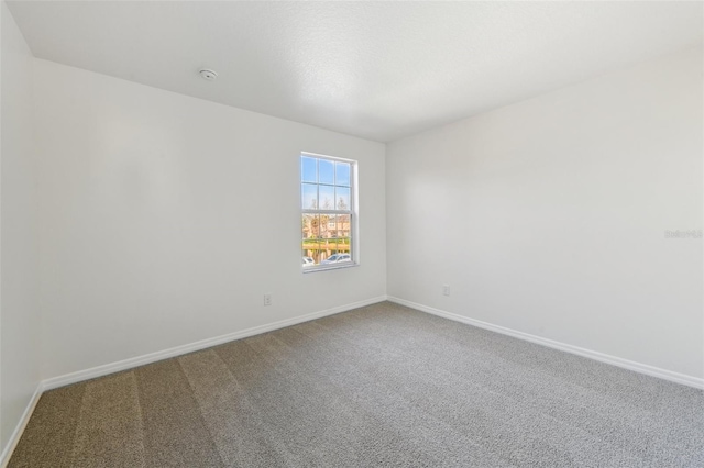 carpeted empty room featuring baseboards