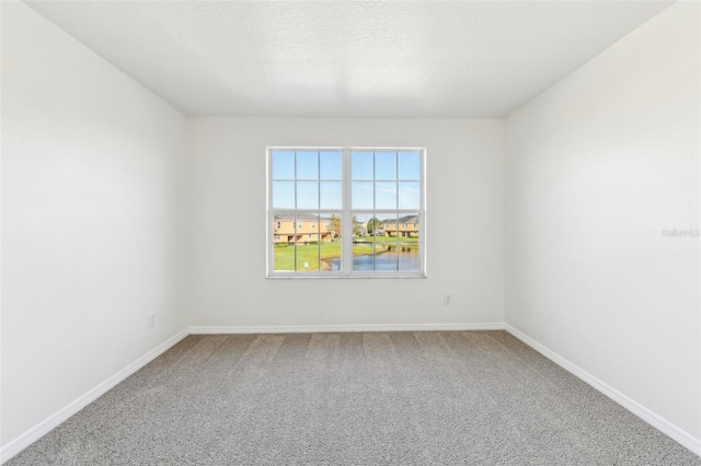 carpeted spare room featuring baseboards and a textured ceiling