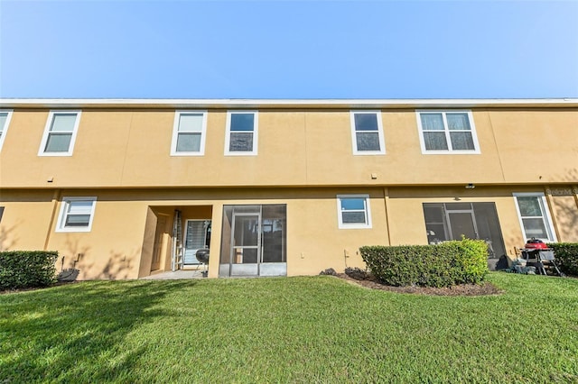 rear view of property with a yard and stucco siding