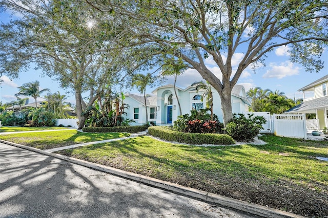 view of front of property with a front yard, a gate, fence, and stucco siding