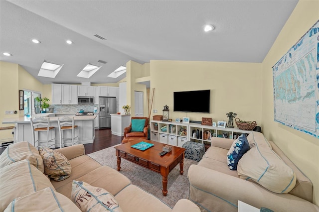 living area featuring a textured ceiling, vaulted ceiling with skylight, recessed lighting, visible vents, and dark wood finished floors