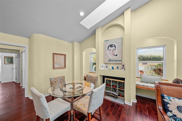 dining space featuring a skylight, recessed lighting, wood finished floors, high vaulted ceiling, and baseboards