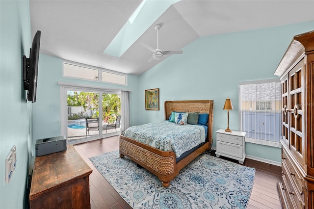 bedroom with access to exterior, vaulted ceiling with skylight, ceiling fan, and hardwood / wood-style floors