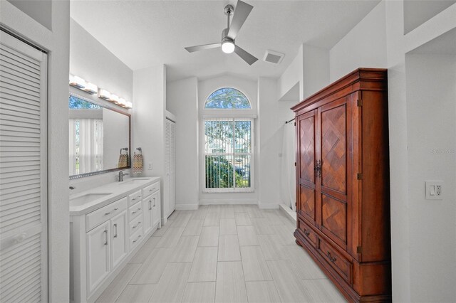 full bath with double vanity, visible vents, vaulted ceiling, and a sink