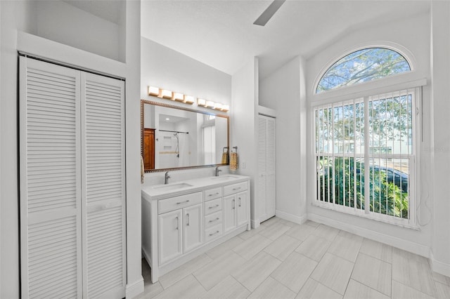 bathroom with a shower, a closet, vaulted ceiling, and a sink