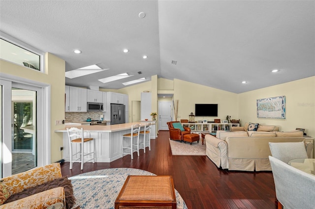 living room featuring a textured ceiling, dark wood-type flooring, lofted ceiling with skylight, and recessed lighting