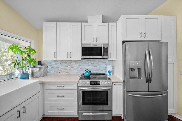 kitchen with backsplash, appliances with stainless steel finishes, white cabinets, and light countertops