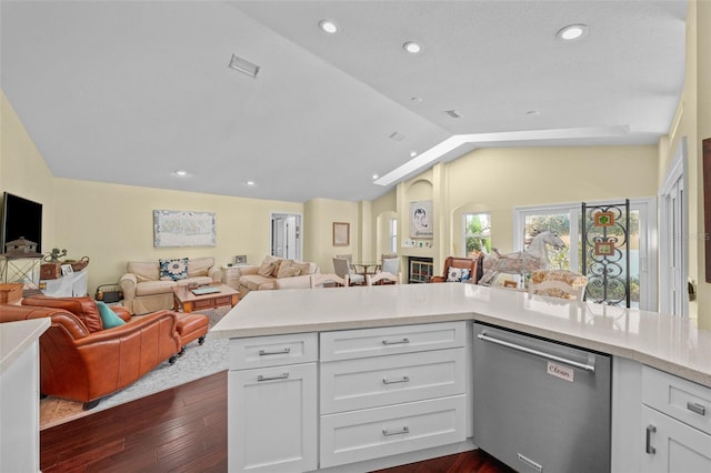 kitchen with lofted ceiling, open floor plan, stainless steel dishwasher, and light countertops