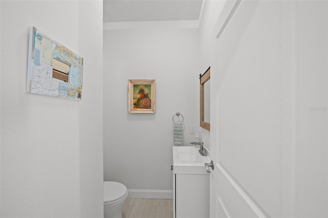 bathroom with toilet, vanity, and baseboards