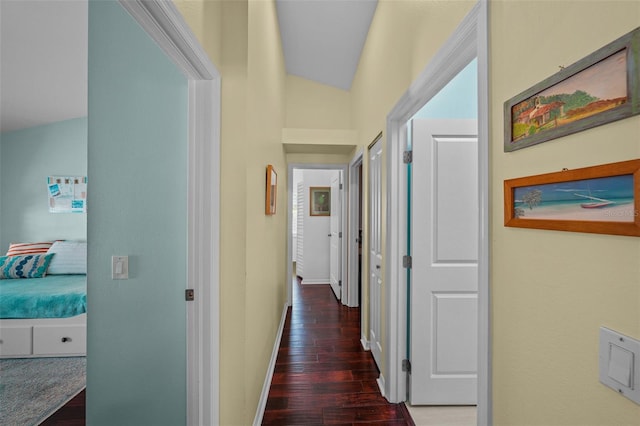 corridor with lofted ceiling, baseboards, and wood finished floors