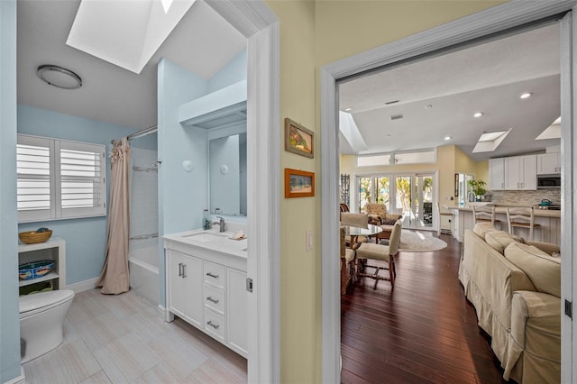 full bathroom featuring baseboards, decorative backsplash, toilet, shower / bath combination with curtain, and vanity