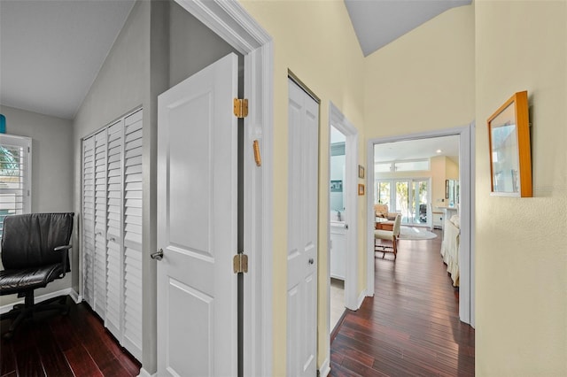 hallway with lofted ceiling, baseboards, and dark wood-type flooring