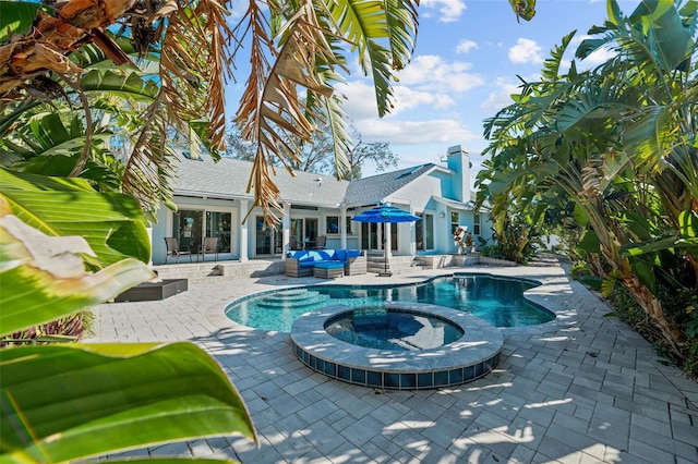 view of pool featuring a pool with connected hot tub, outdoor lounge area, and a patio