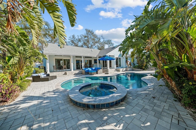 view of swimming pool featuring a pool with connected hot tub, outdoor lounge area, and a patio