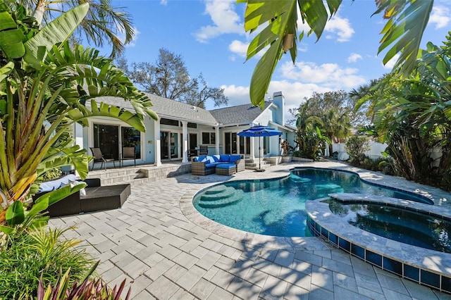 view of pool featuring a pool with connected hot tub, a patio area, and an outdoor living space