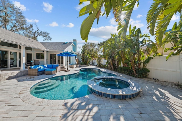 view of pool featuring a pool with connected hot tub, outdoor lounge area, a patio, and fence