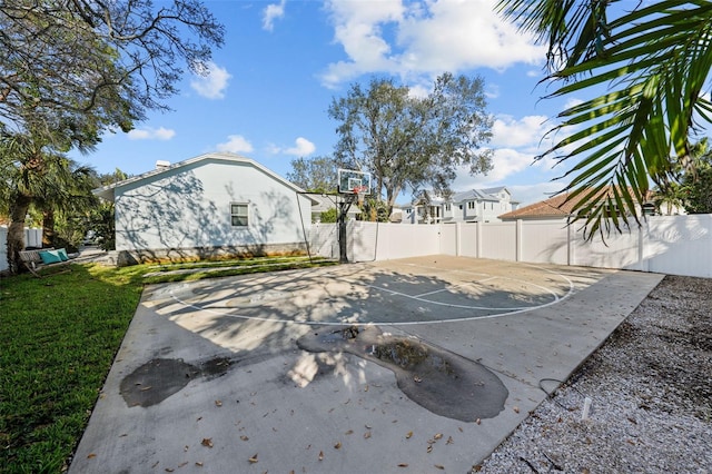 view of sport court featuring basketball hoop, a yard, and a fenced backyard