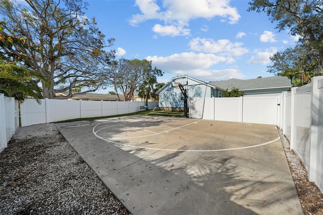 view of sport court with a fenced backyard and basketball hoop