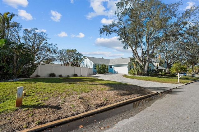 view of front of home with a garage, fence, decorative driveway, and a front yard