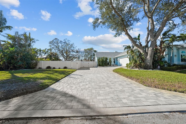 view of front of property with a garage, a front yard, decorative driveway, and fence