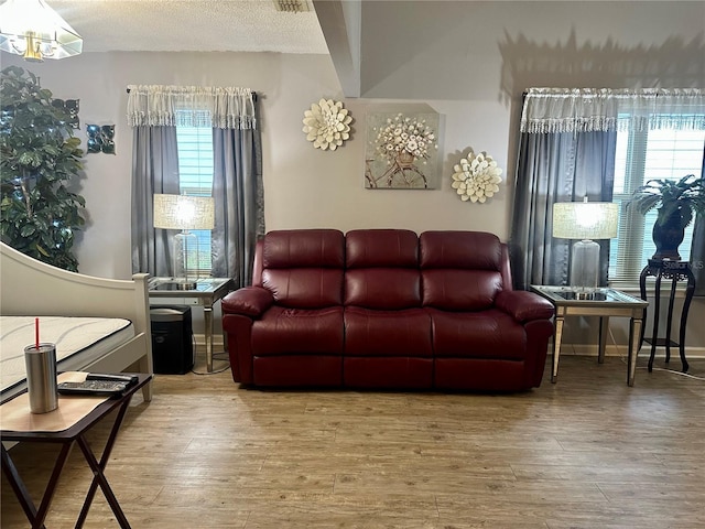 living area featuring a textured ceiling, wood finished floors, and baseboards