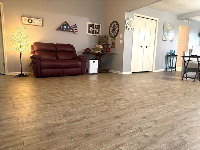 living room with a textured ceiling, baseboards, and wood finished floors