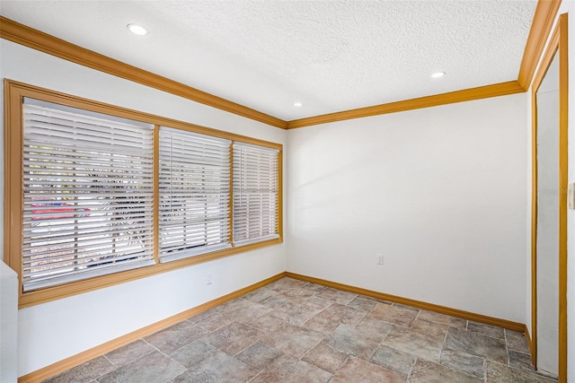 spare room featuring a textured ceiling, crown molding, stone finish floor, and baseboards